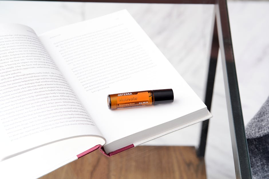 Essential oil bottle on an open book on a glass table captures a relaxing atmosphere.