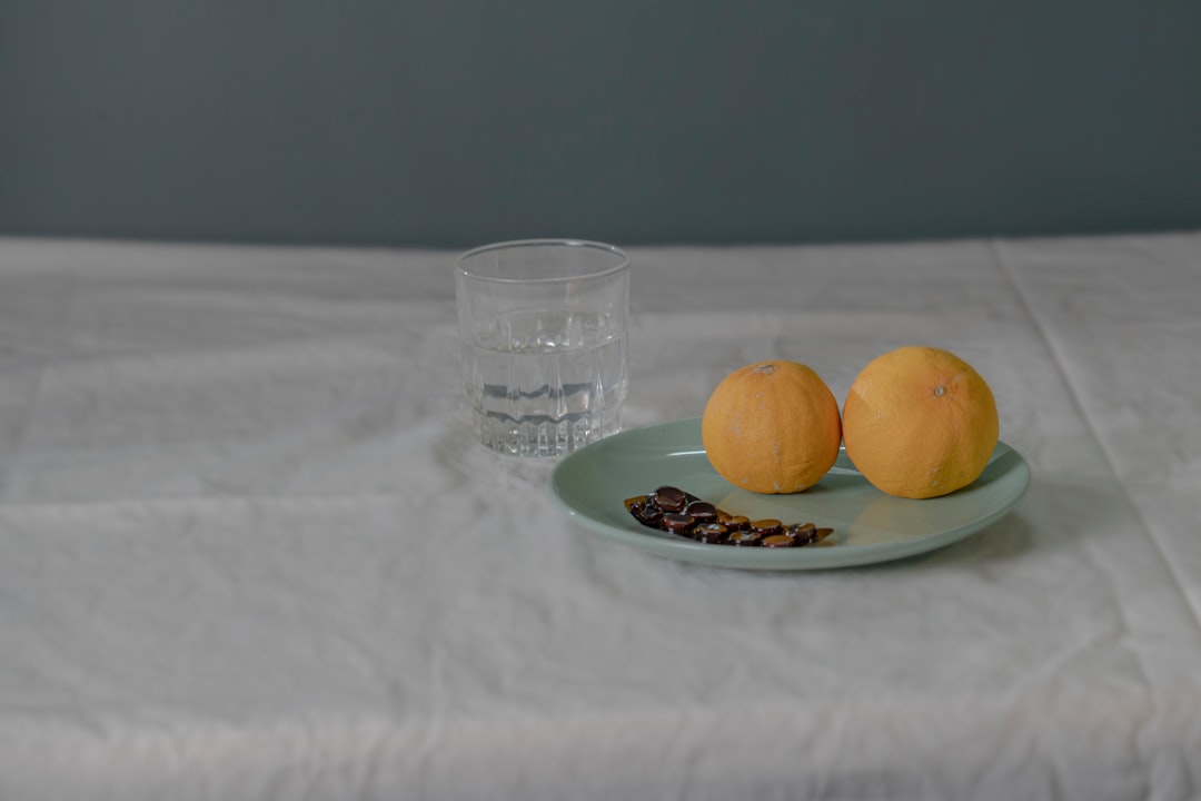two oranges on a plate with a glass of water