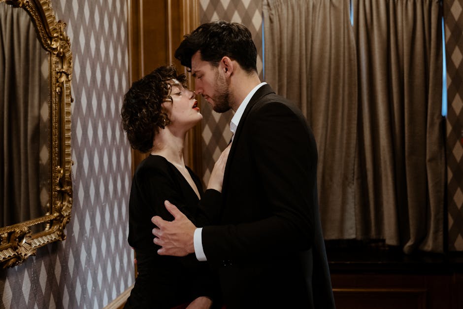 A fashionable couple embraces indoors, captured in an intimate and elegant moment of love.