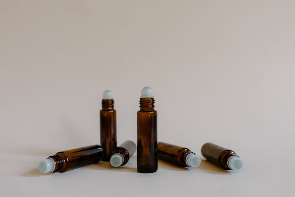 Five brown roller bottles on white background ideal for aromatherapy use.