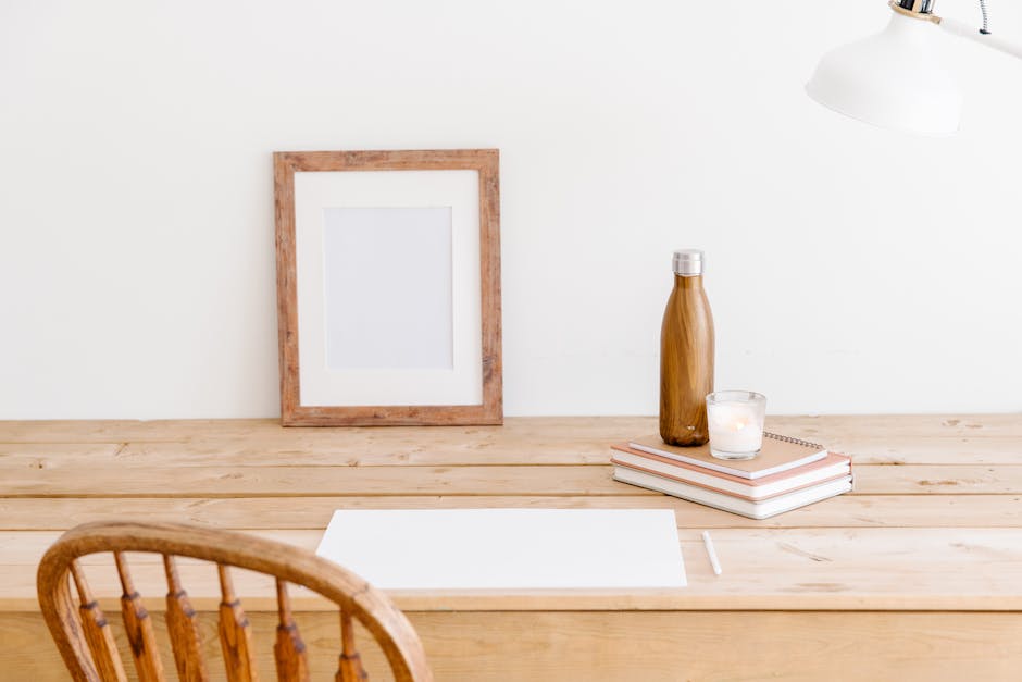 Minimalist workspace featuring a wooden chair, desk, frame, and bottle. Perfect for a calm office setting.