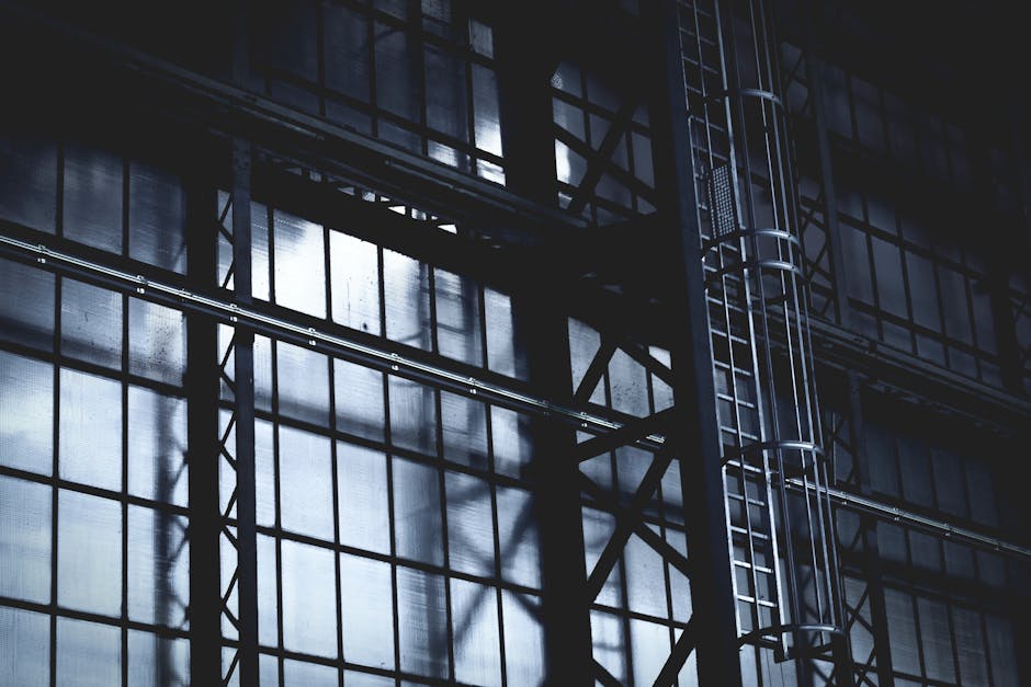 Dramatic view of a steel frame and ladder in an industrial setting with sunlight casting shadows.