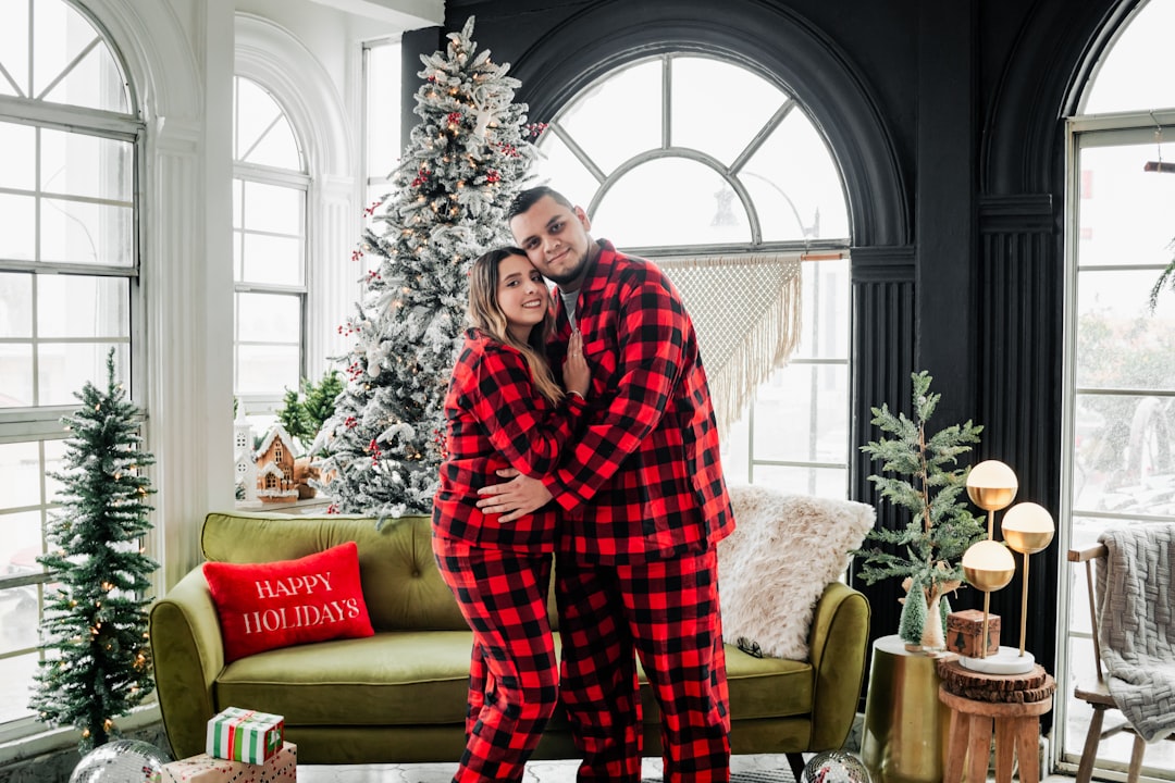 a man and a woman in pajamas standing in front of a christmas tree