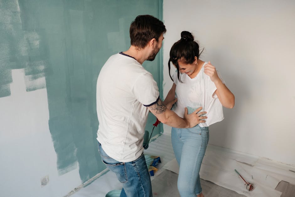 Happy couple having fun painting walls together during a home renovation project.