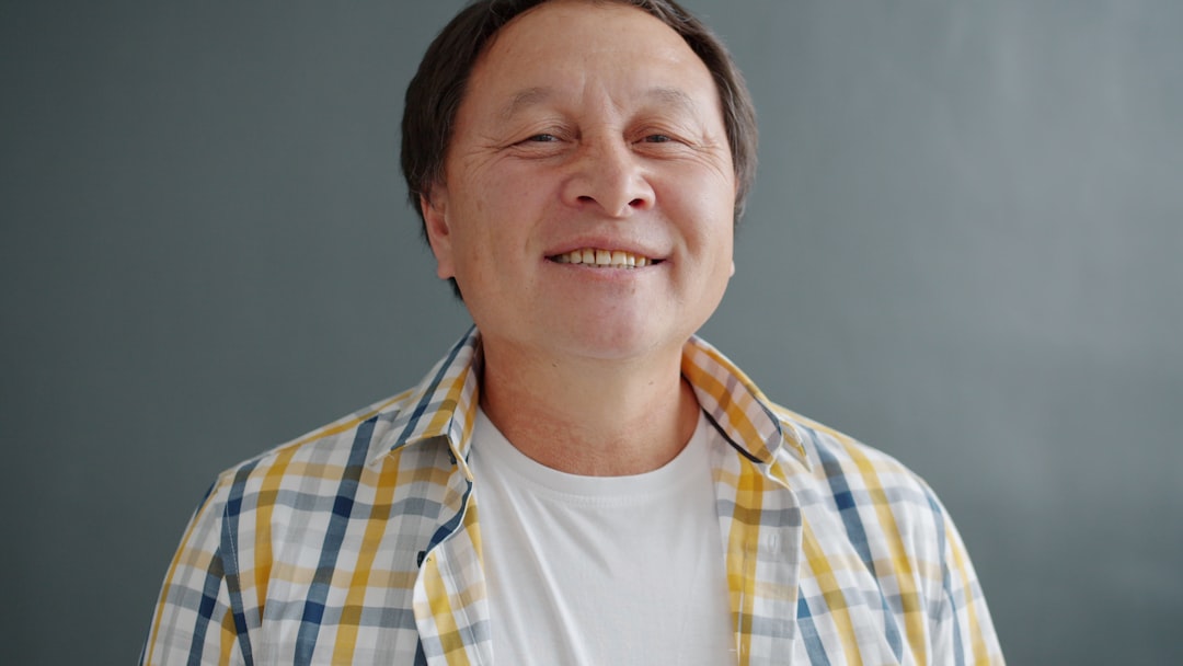 Smiling man in plaid shirt against gray background