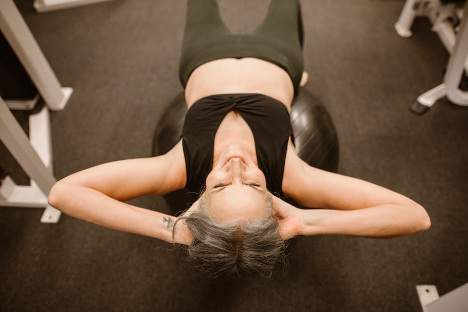 Senior woman performing exercise on stability ball for fitness and strength.