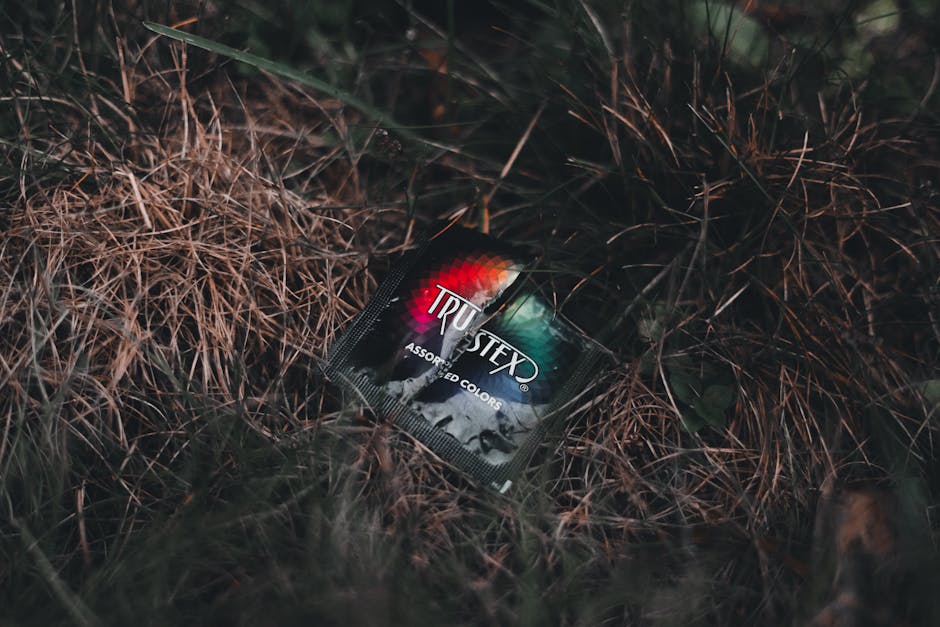 Trustex condom packet lies on grass, highlighting protection and safety themes.