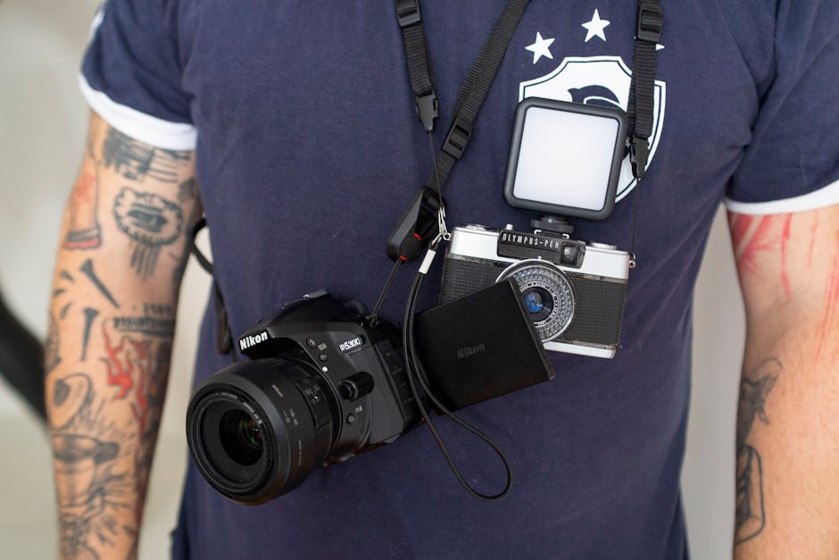 Close-up of a photographer wearing a Nikon DSLR and Olympus Pen camera.