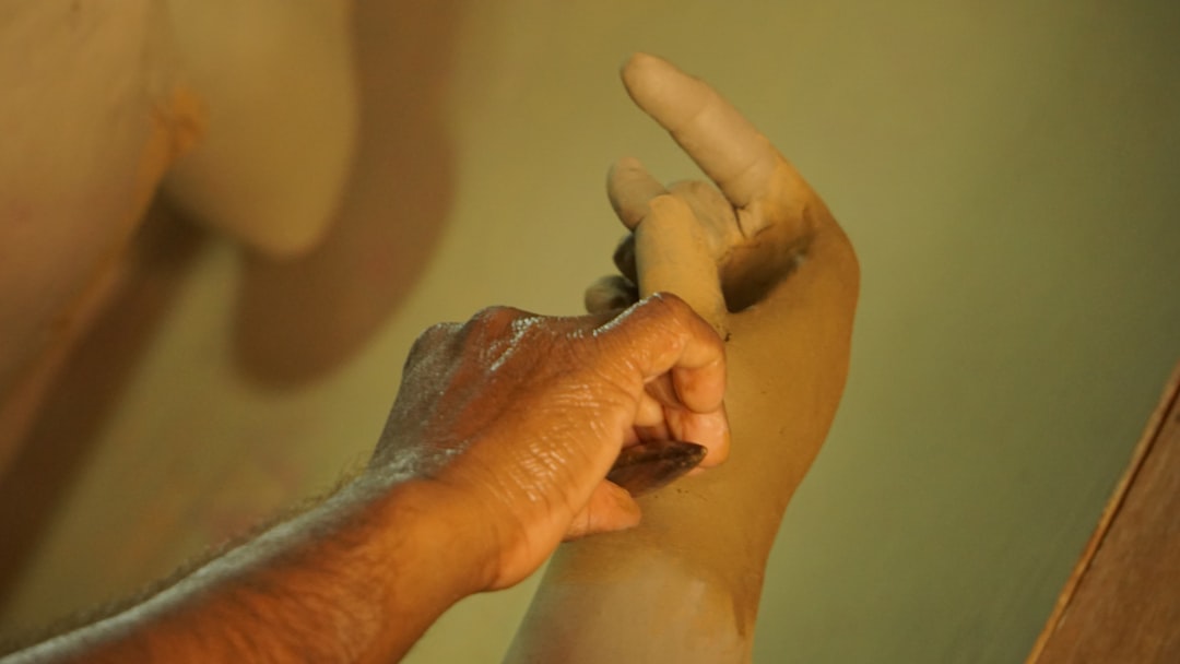 A hand molds clay.