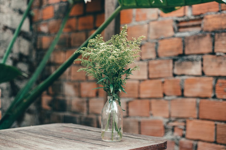 A vase of green flowers against a rustic brick wall, showcasing a natural and earthy ambiance.
