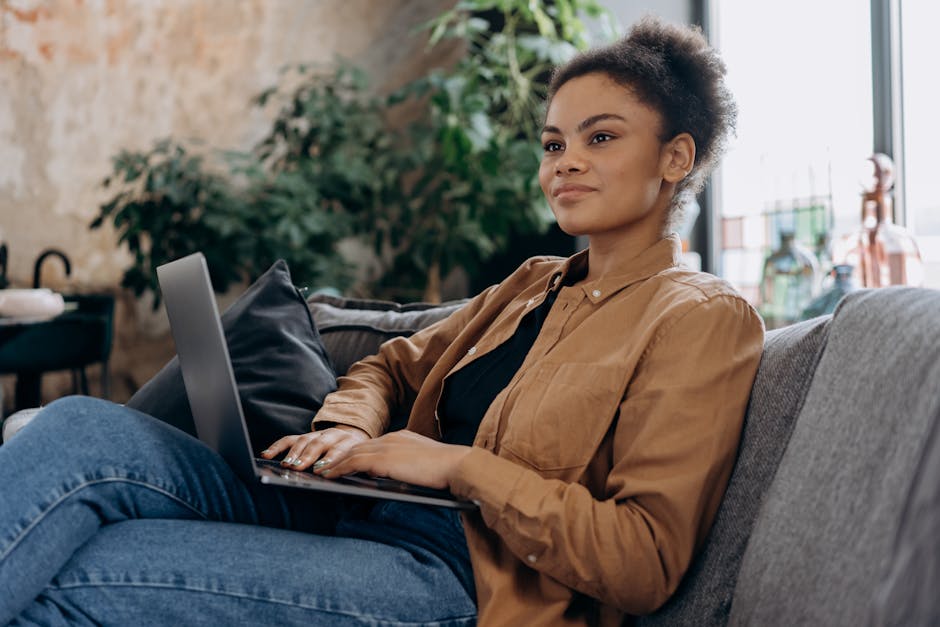 A confident woman working remotely on a laptop, sitting comfortably at home.