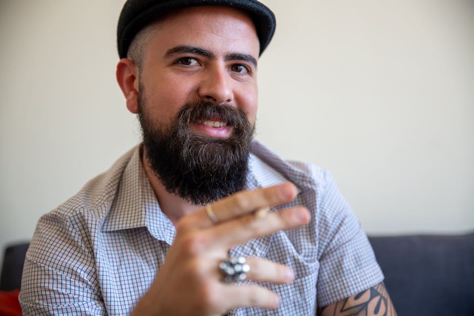 Portrait of a happy bearded man wearing a checkered shirt, smiling indoors.
